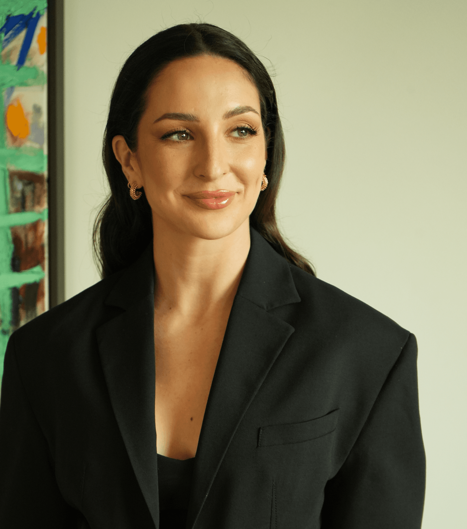 Anne-Sophie Fluri in a black blazer, photographed from the waist up beside a painted canvas