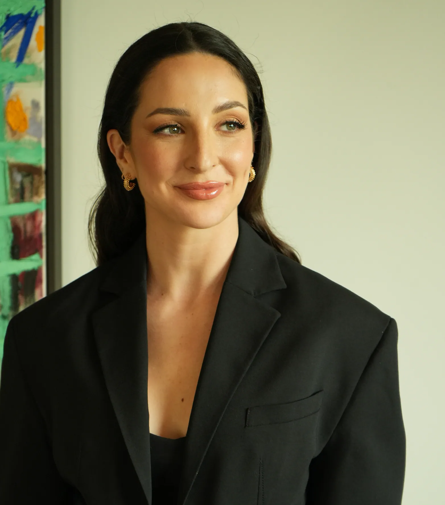Anne-Sophie Fluri in a black blazer, photographed from the waist up beside a painted canvas