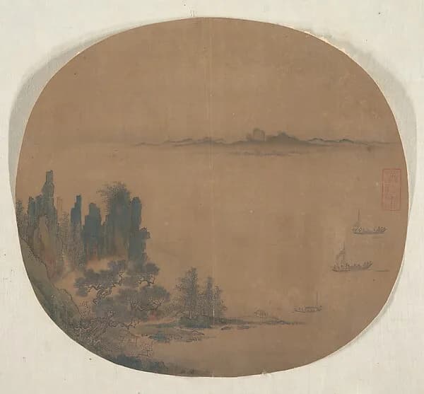 A round fan painting of a misty sea with a few small boats and a faint shoreline, in ink on tan silk