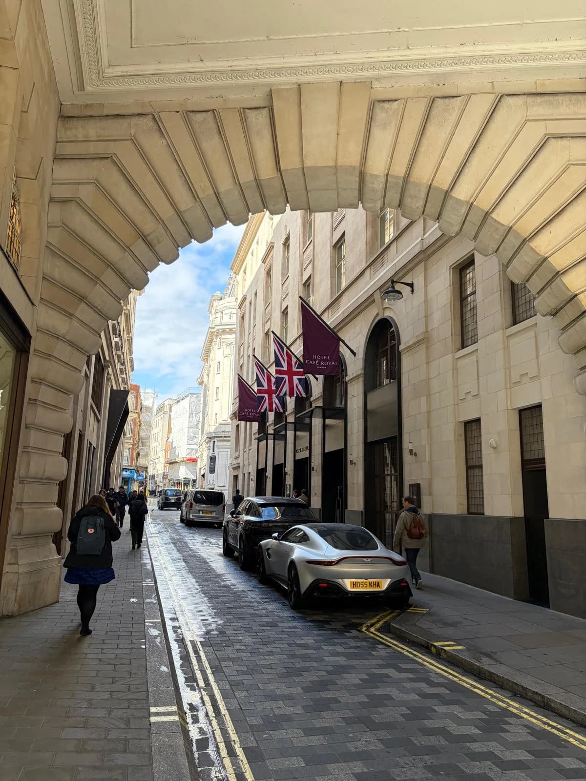 Hotel Cafe Royal's entrance beneath its flags, with cars parked along the street