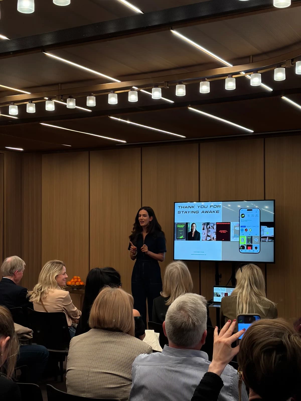 Anne-Sophie speaking beside her closing presentation slide, with guests seated in front of her at Hotel Cafe Royal
