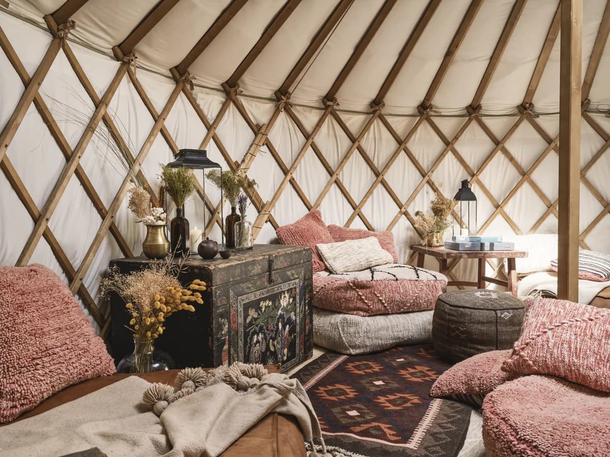Cushioned seating, lanterns and dried flowers inside a timber-framed yurt at CERVO
