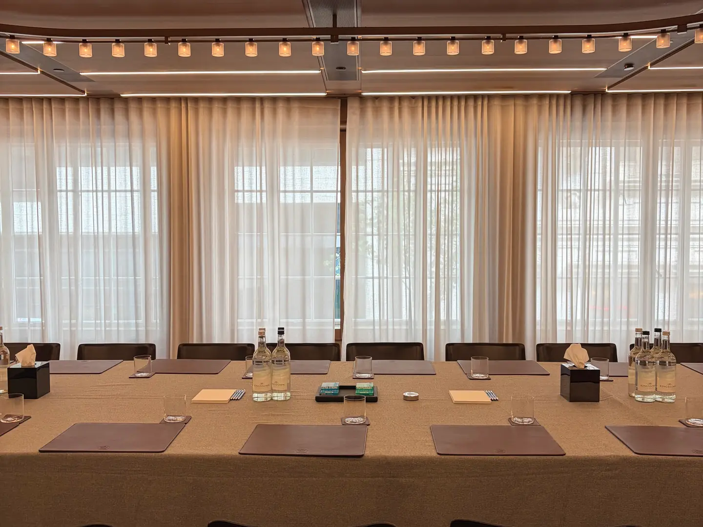 A panelled private room at Hotel Cafe Royal, set with a long table, leather mats and tall curtained windows