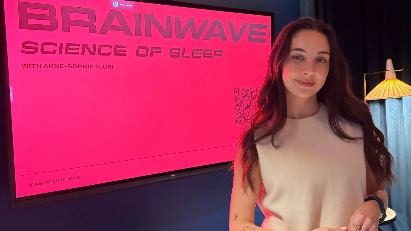 Anne-Sophie Fluri standing beside the title card for her Science of Sleep talk at Lighthouse Social, shown on a wall-mounted screen