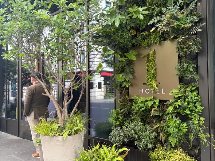 The 1 Hotel entrance sign set into a living wall of ferns beside the street