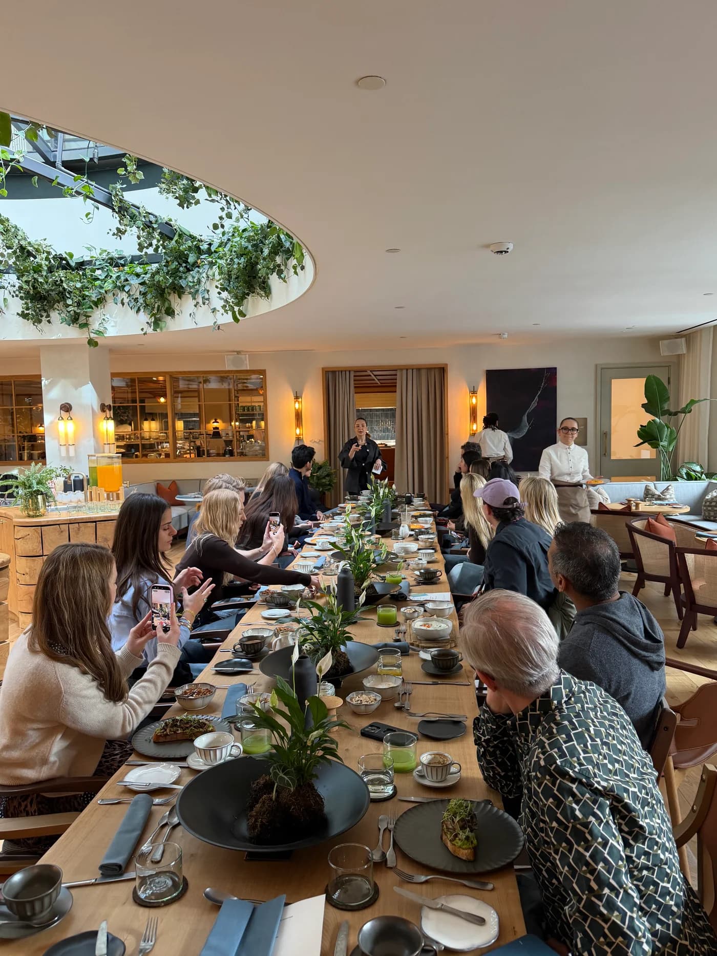 Anne-Sophie speaking at the far end of a communal table as guests look towards her at a Six Senses London neuroscience brunch