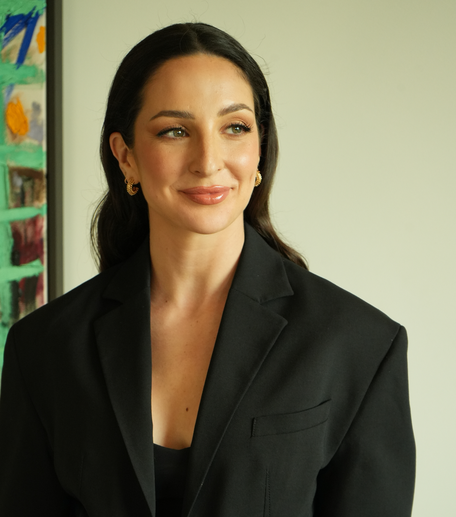 Anne-Sophie Fluri in a black blazer, photographed from the waist up beside a painted canvas