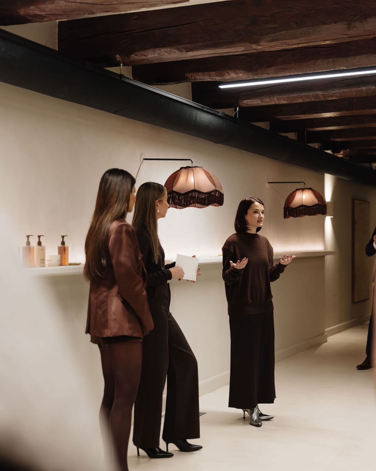 A host welcoming guests beside a display shelf